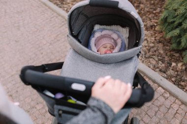 Anne dışarıda yeni doğmuş bir bebekle geziniyor. Annelerin elleri. Birinci kişi görünümü