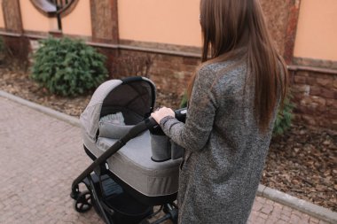 Genç Anne, Bebek arabası içinde yenidoğan bebeği ile yürüyor. Gri bir Pram. Güzel anne içinde Sunglasses