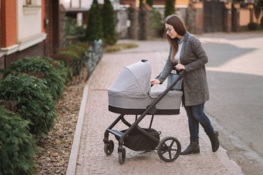 Genç Anne yürümek ile kız içinde Stroller. Annem bebeği önemsiyor. Anne Puset için bakmak ve bebek uyku yardım