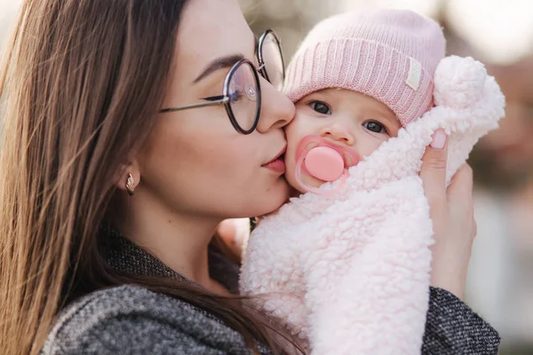 Portret van moeder en haar kleine baby meisje. Mooie moeder en schattige baby. Moeder HUD haar dochter. Baby gekleed in peanch kleur hoed en tepel speelgoed — Stockfoto