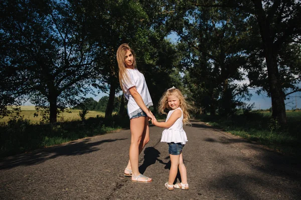 Mother and little daughter walk though the alley and hold each others hands — Stock Photo, Image