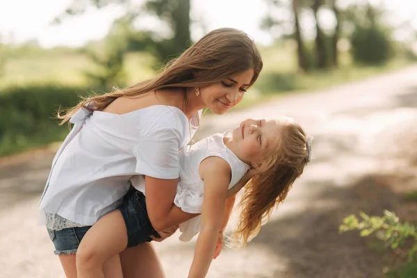 Little girl playing with mom in the park in summer day during the sunset spin around — Stock Photo, Image