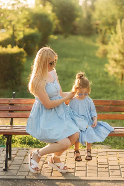 Maminka a jeho malá dcera sedí na lavičce v parku — Stock fotografie