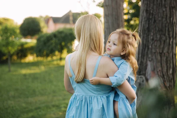 Young beautiful woman with her little cute daughter. Young daughter hugs mother in summer park — Stock Photo, Image