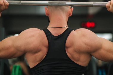 Siyah tişörtlü adam spor salonunda halter kullanır. Bodyduilder eğitimi. Geri görünüm