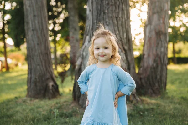 Klein meisje in blauwe jurk lopen in park — Stockfoto