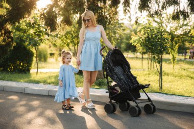 küçük kızı anne bebek arabası itme yardımcı olur.