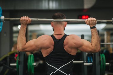 Siyah tişörtlü adam spor salonunda halter kullanır. Bodyduilder eğitimi. Geri görünüm