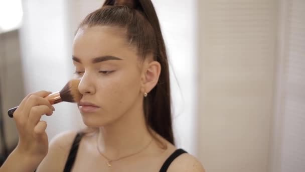 Maquiagem artista trabalho em seu estúdio de beleza. Mulher aplicando pelo mestre de maquiagem profissional. Linda maquiagem artista fazer uma maquiagem para ruiva modelo com sardas. Ela usa uma paleta. — Vídeo de Stock