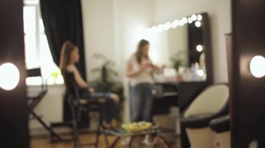 Güzellik stüdyosu modeli ile makyaj sanatçısı çalışma. Şık Kızıl saçlı model için moda yapmak