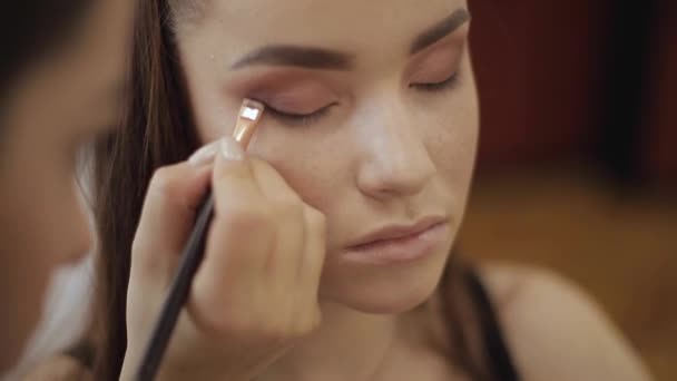 Makeup artist applies eye shadow, perfect evening makeup. Beauty redhead girl with perfect skin and freckles — Stock Video