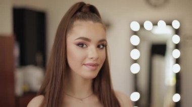 Güzellik stüdyosu salonda güzel makyaj ile genç çekici kadın Portresi. Akşam makyaj. Aynanın ışığının arka planı