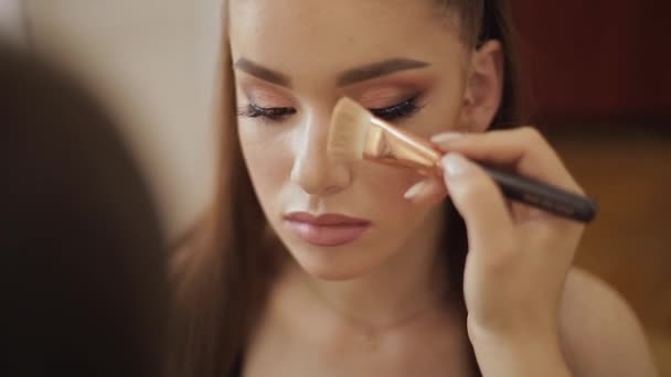 Make-up-Meisterinnen verwenden einen Puderpinsel. schönes Modell im Schönheitsstudio. professionelle Make-up-Artist beenden Mode Maleup. Hintergrund des weißen Klappbildschirms — Stockvideo