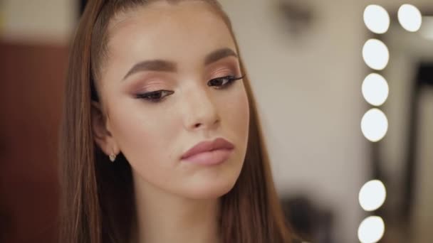 Porträtt av ung attraktiv kvinna med vacker makeup i Beauty Studio Salon. Kvälls smink. Bakgrund av ljus av spegel — Stockvideo