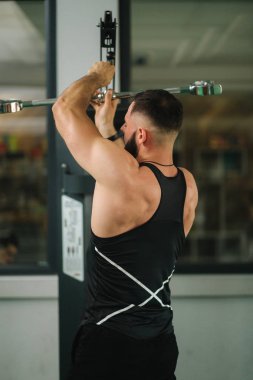 Genç bir atlet spor salonunda antrenman yaptı. Sırt ve göğüs kaslarını gösterir. Geri görünüm