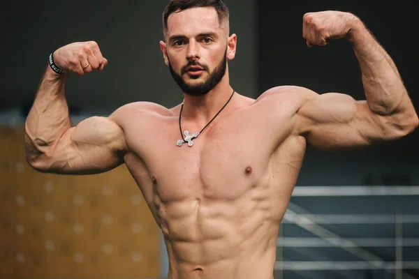 Un joven atleta entrena en el gimnasio. Muestra los músculos del torso —  Fotos de Stock