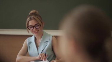 Çocukların önünde kadın öğretmen. Sınıfta ki güzel öğretmen masada oturup çocuklara soruyor. eğitim, ilkokul, öğrenme ve insan kavramı