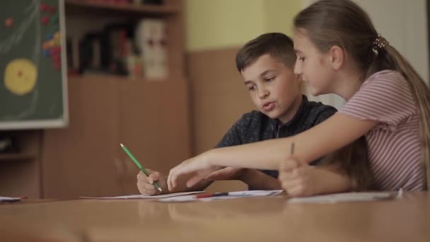 Utbildning, grundskola. Lärande och människor koncept - grupp av skolbarn med pennor och anteckningsböcker skrivprov i klassrummet — Stockvideo