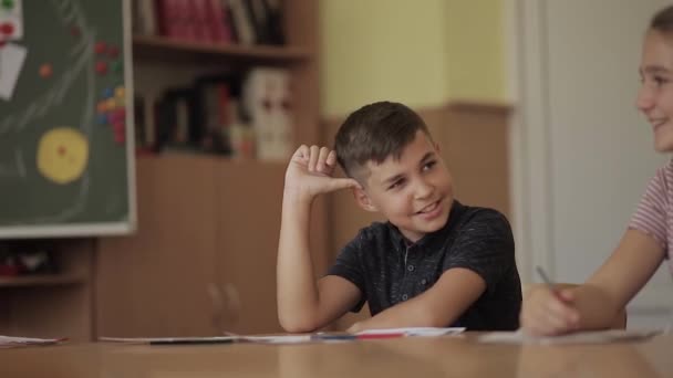 Educación, escuela primaria. Concepto de aprendizaje y personas - grupo de escolares con bolígrafos y cuadernos prueba de escritura en el aula — Vídeos de Stock