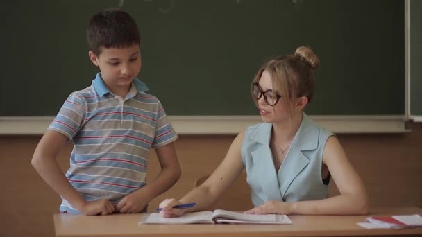 Όμορφη δασκάλα στην τάξη κάθεται στο γραφείο και ρωτάει τα παιδιά. εκπαίδευση, Δημοτικό σχολείο, μάθηση και αντίληψη των ανθρώπων — Αρχείο Βίντεο
