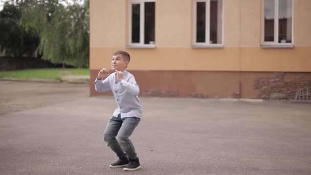 Rapaz feliz salta e levanta as mãos. Contexto da escola — Vídeo de Stock