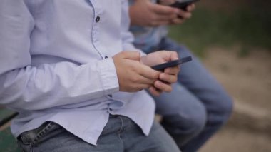 Genç çocuk Bench üzerinde oturan ve okul molası sırasında online oyunlar oynamak yakın