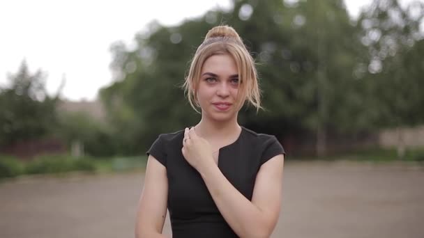 Joven techer femenina atractiva en vestido negro con gafas de sol de pie fuera. Antecedentes escolares — Vídeo de stock