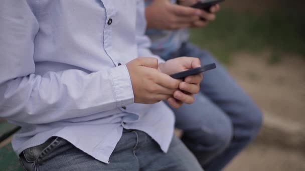 Κοντινό πλαίσιο του νεαρού αγοριού που κάθεται στον πάγκο και να παίξει διαδικτυακά παιχνίδια κατά τη διάρκεια του σχολικού διαλείμματος — Αρχείο Βίντεο