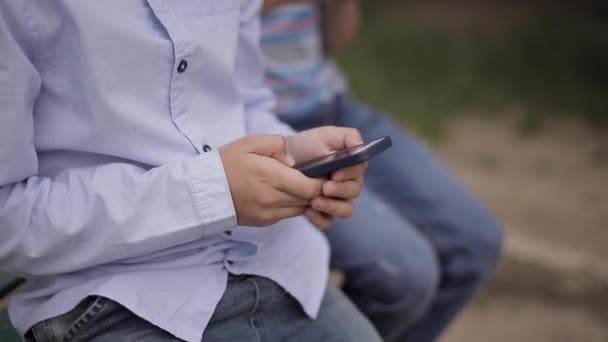 Primer plano de niño sentado en el banco y jugar juegos en línea durante las vacaciones escolares — Vídeos de Stock