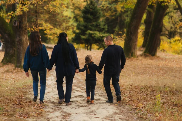 Feliz familia caminando por el parque. Mamá papá y dos hijas. Vista trasera — Foto de Stock