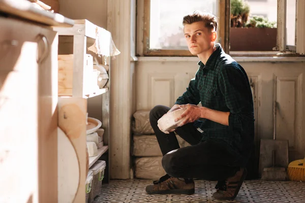 Man potter looking for ware for a work. Young man potter in his workshop. Handsome man work