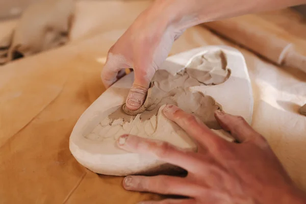 Las manos de alfarero llenan la forma con una cerámica en forma de mariposa. Primer plano de las manos — Foto de Stock
