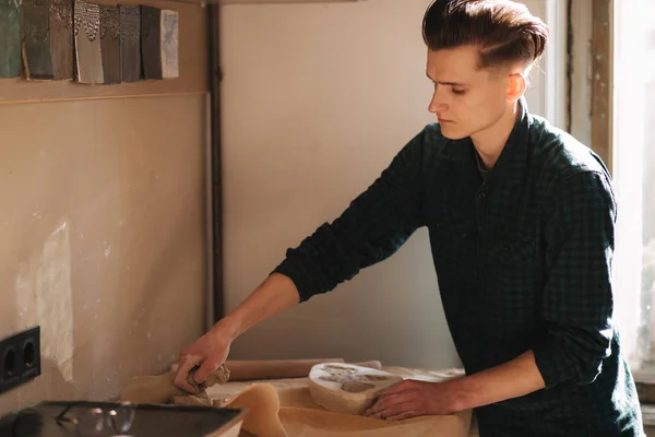 Man pottenbakker op zoek naar spullen voor een werk. Jongeman pottenbakker in zijn werkplaats. Knappe man werk — Stockfoto