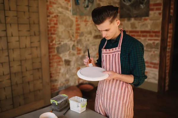 Pottenbakker maken ornament op keramische plaat. Professionele mannelijke pottenbakker teken een potlood op keramisch product — Stockfoto