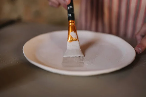 Närbild av keramiker händer gör prydnad på keramiska produkt. Tallrik i manliga händer. Ung konstnär — Stockfoto