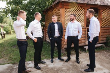 Handsome groom with his groomsman on the backyard. Five man. Groom dressed in suit, gromsmen in white shirt. Funny guys on the wedding clipart