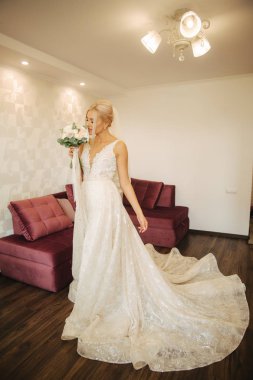 Güzel düğün elbisesi ile buket evde içinde zarif gelin. Sarı saçlı kadın güzel makyaj ve saç modeli ile