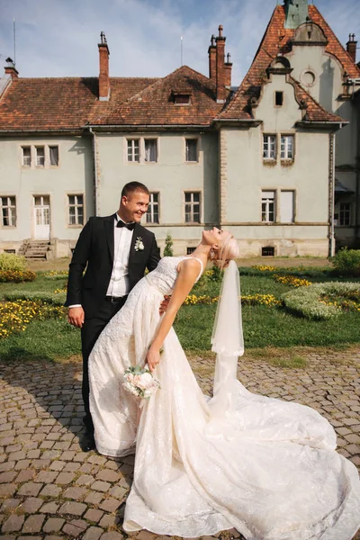 Casal elegante no parque junto ao castelo. Linda noiva com seu belo marido — Fotografia de Stock