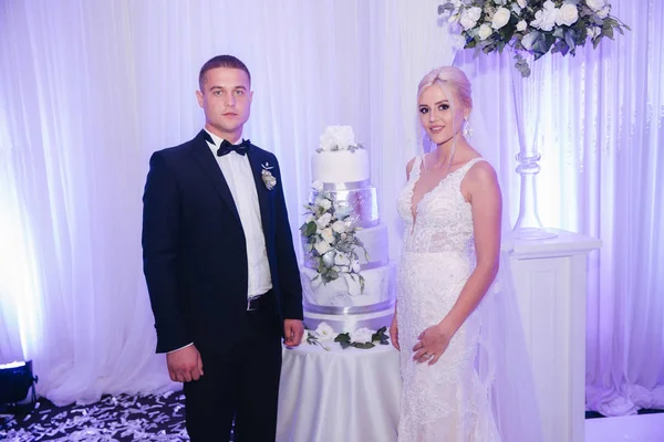 레스토랑에서 아름다운 신랑과 신부는 웨딩 케이크 근처에 서있다. 신혼 부부 — 스톡 사진