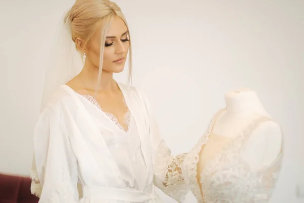 Ochtend van prachtig blond haar bruid in de buurt van de trouwjurk — Stockfoto