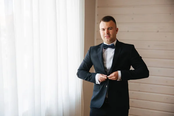 Junger Bräutigam in seinem Haus. schöner Mann im Hochzeitsanzug lächelt — Stockfoto