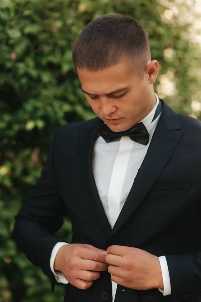 Junger Mann beim Spazierengehen im Park. schöner Bräutigam im schwarzen Anzug — Stockfoto