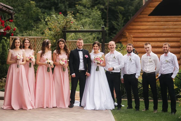Bräutigam und Braut stehen mit Bräutigam und Brautjungfer draußen. Frischvermählte küssen sich und Freund klatscht. Hochzeitstag — Stockfoto