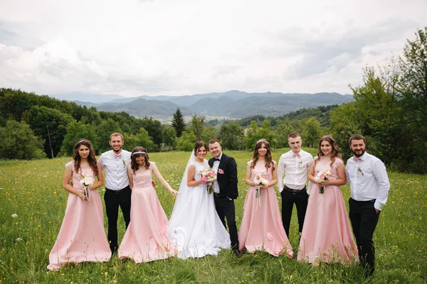 Damat ve gelin sağdıç ve nedime ile stand. Arkadaş grubu öpüşme yeni evliler. Düğün günü. Mountsins arka plan — Stok fotoğraf