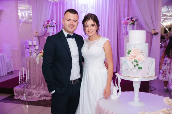 Жених и невеста в ресторане стоят у свадебного торта — стоковое фото