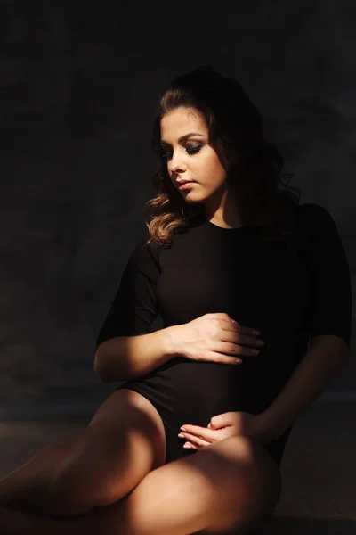 Young pregnant woman sit near the window. Sun rays fall on woman — Stock Photo, Image