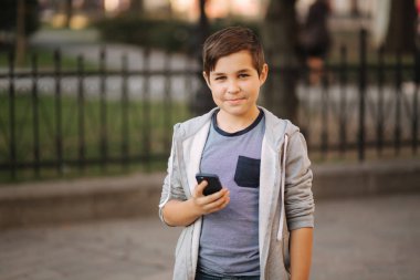 Genç çocuk smaptphone ile oynuyor. Sokakta cep telefonu kullanarak Schoolboy