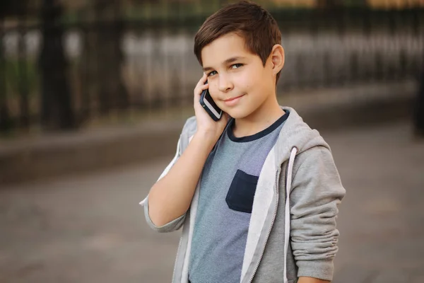 Un chico joven llama a su madre. Adolescente chico uso de teléfono fuera — Foto de Stock