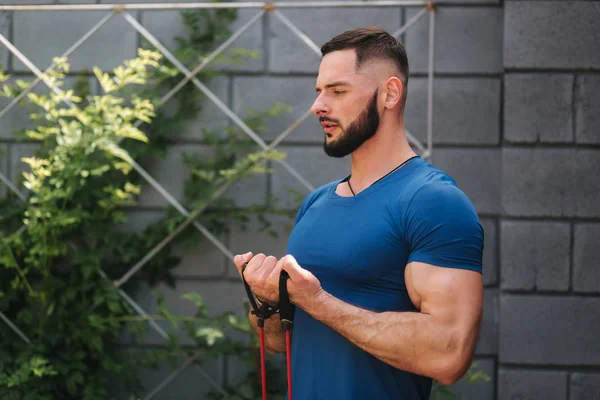 Male bodybuilder trains with resistance band. Bearded man working out with elastic band — Stock Photo, Image