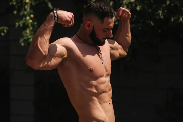 Joven hombre barbudo culturista mostrar sus músculos fuera después del entrenamiento —  Fotos de Stock